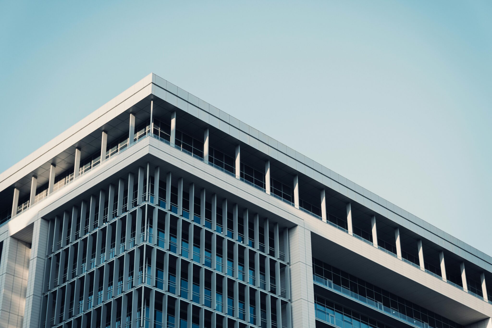 Comprar una Empresa en Colombia: 10 Cosas que Debe Saber Antes de Firmar Contemporary office building with a futuristic glass facade reflecting the sky.